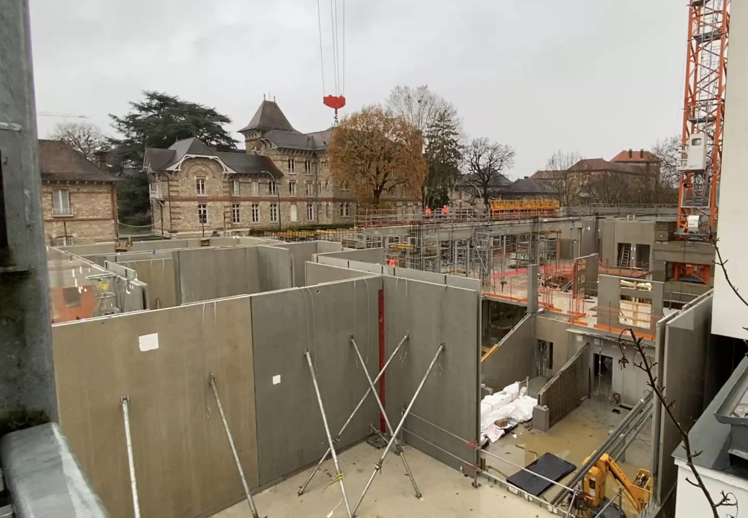 Photo d'un chantier. Des murs en bétons se dressent. Des ouvriers travaillent.