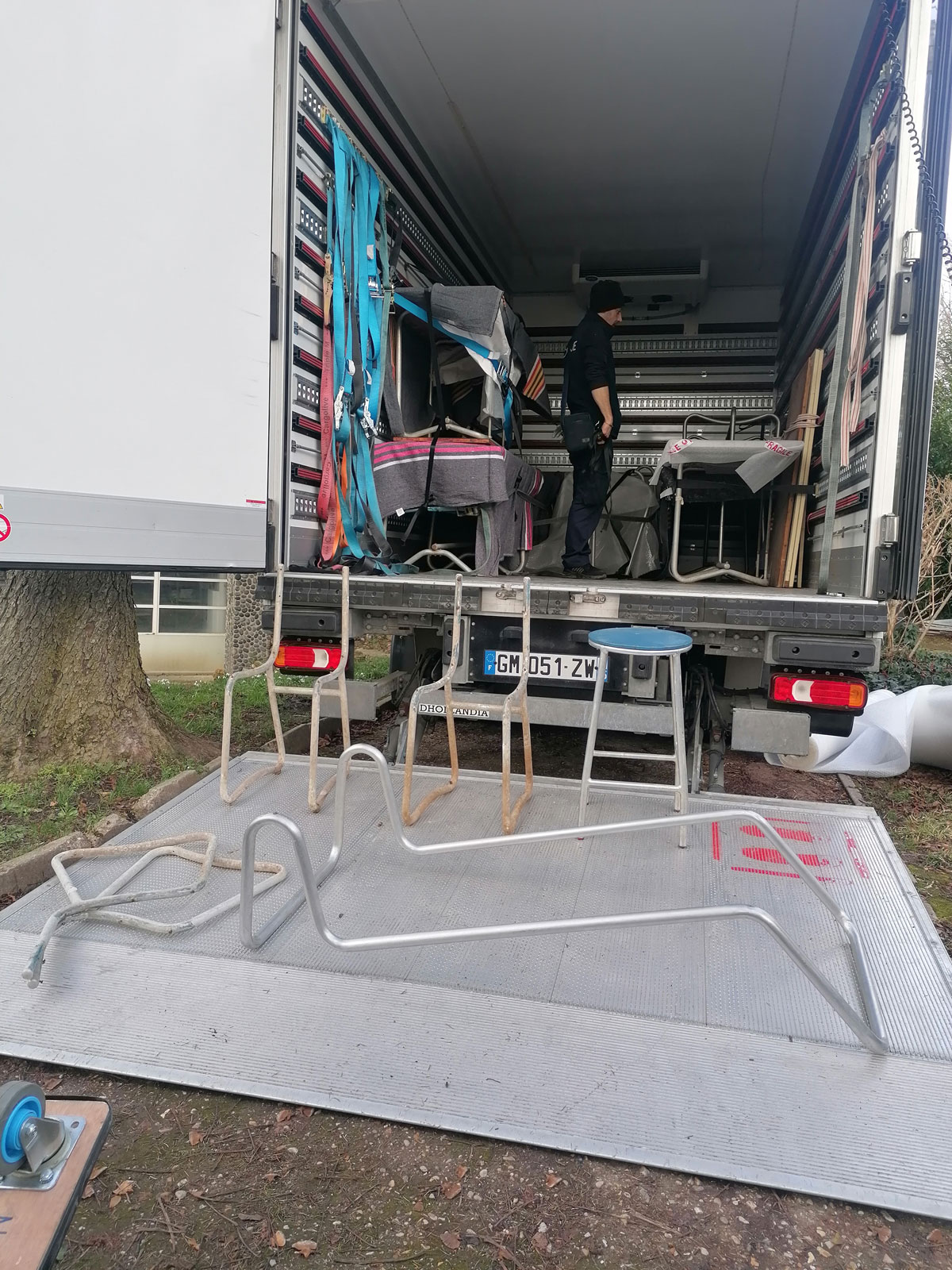 Un camion avec plusieurs pièces de mobilier : chaise, transat, tables.