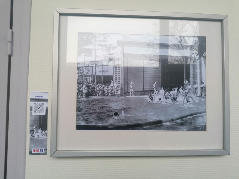 Photo d'un cadre avec une photo d'un des bassins de l'école de plein air avec des élèves se baignant.