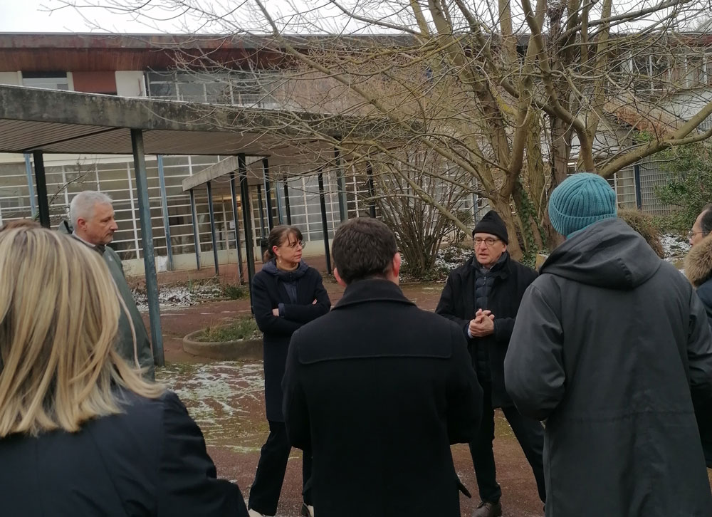 Plusieurs personnes discutent dans une des cours de l'école de plein air. 