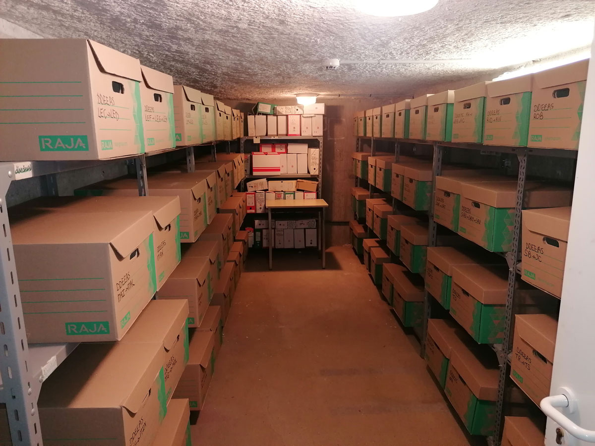 Cave avec des cartons posés sur des étagères.