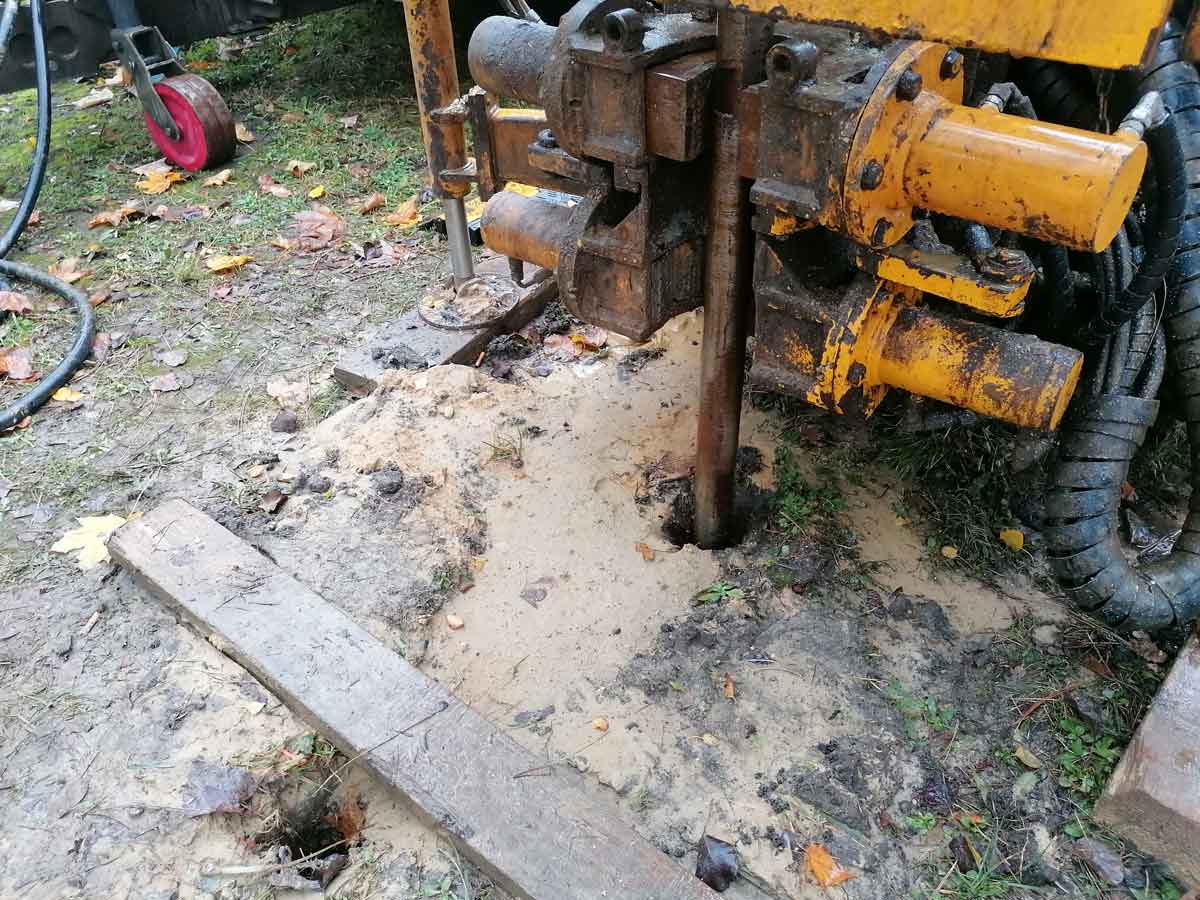 Photo d'une foreuse avec un grand tube enfoncé dans une pelouse.